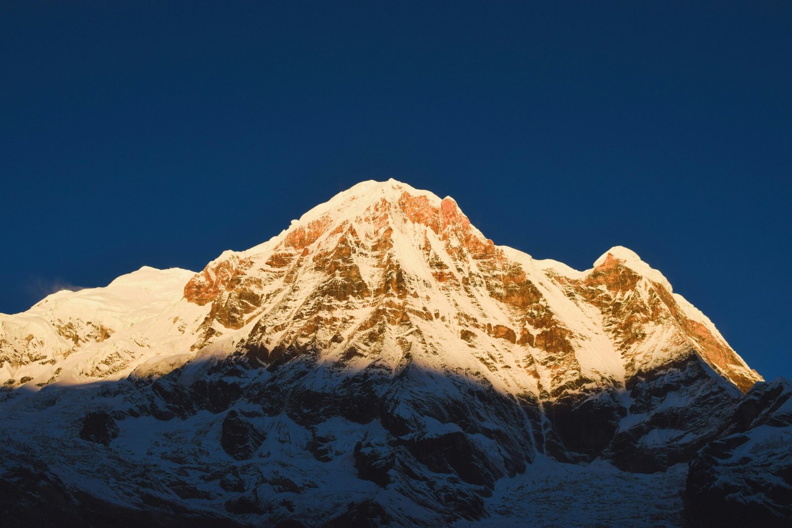 the top of a snow covered mountain against a blue sky